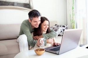 Beautiful young couple relaxing in a living room and using laptop