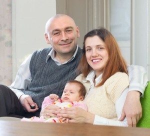 Happy family of three with newborn baby at home interior